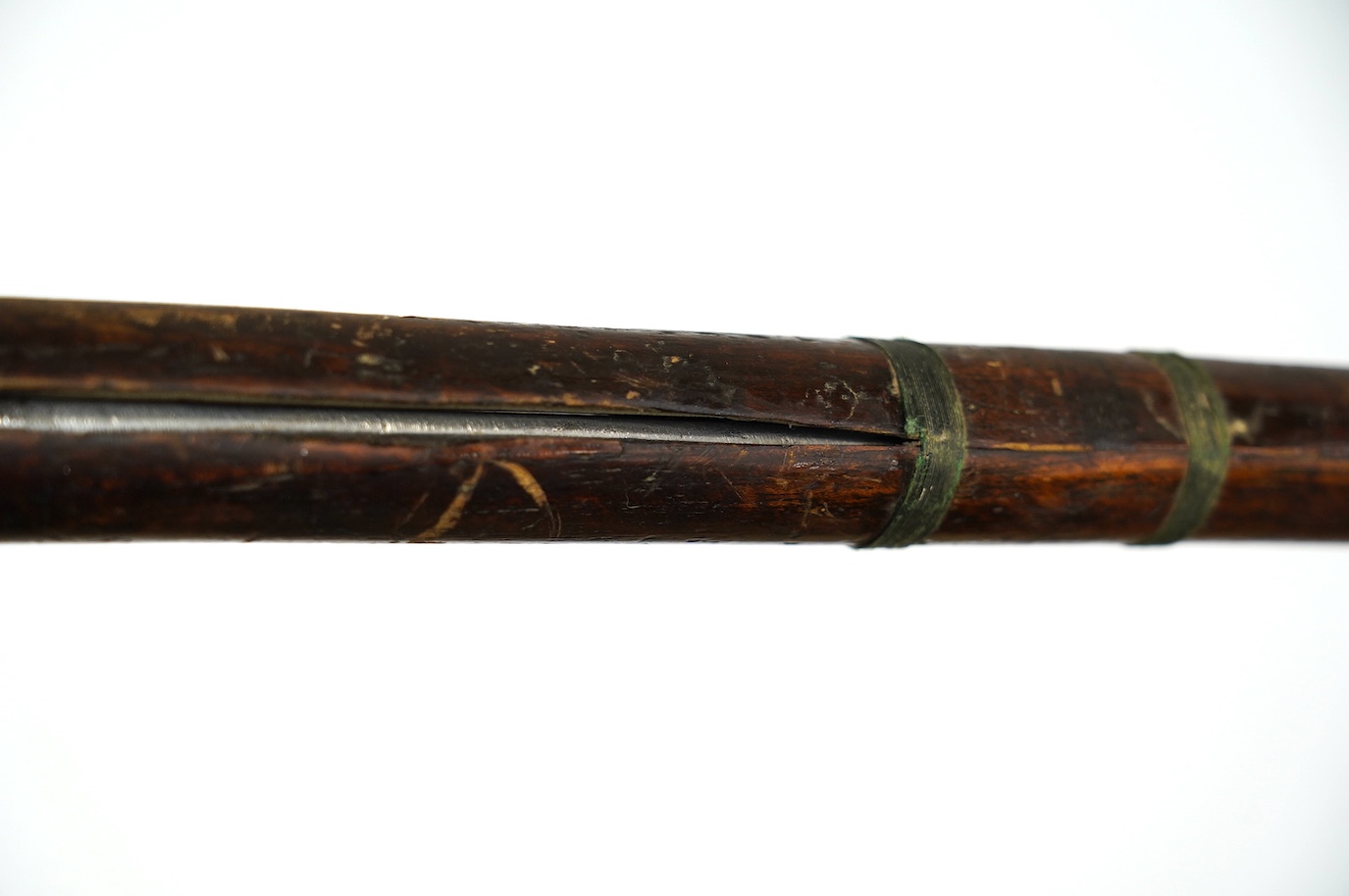 A Burmese sword Dha, curved single edge blade, hilt bound with platted rattan, in its wooden scabbard, blade 60cm. Condition - fair